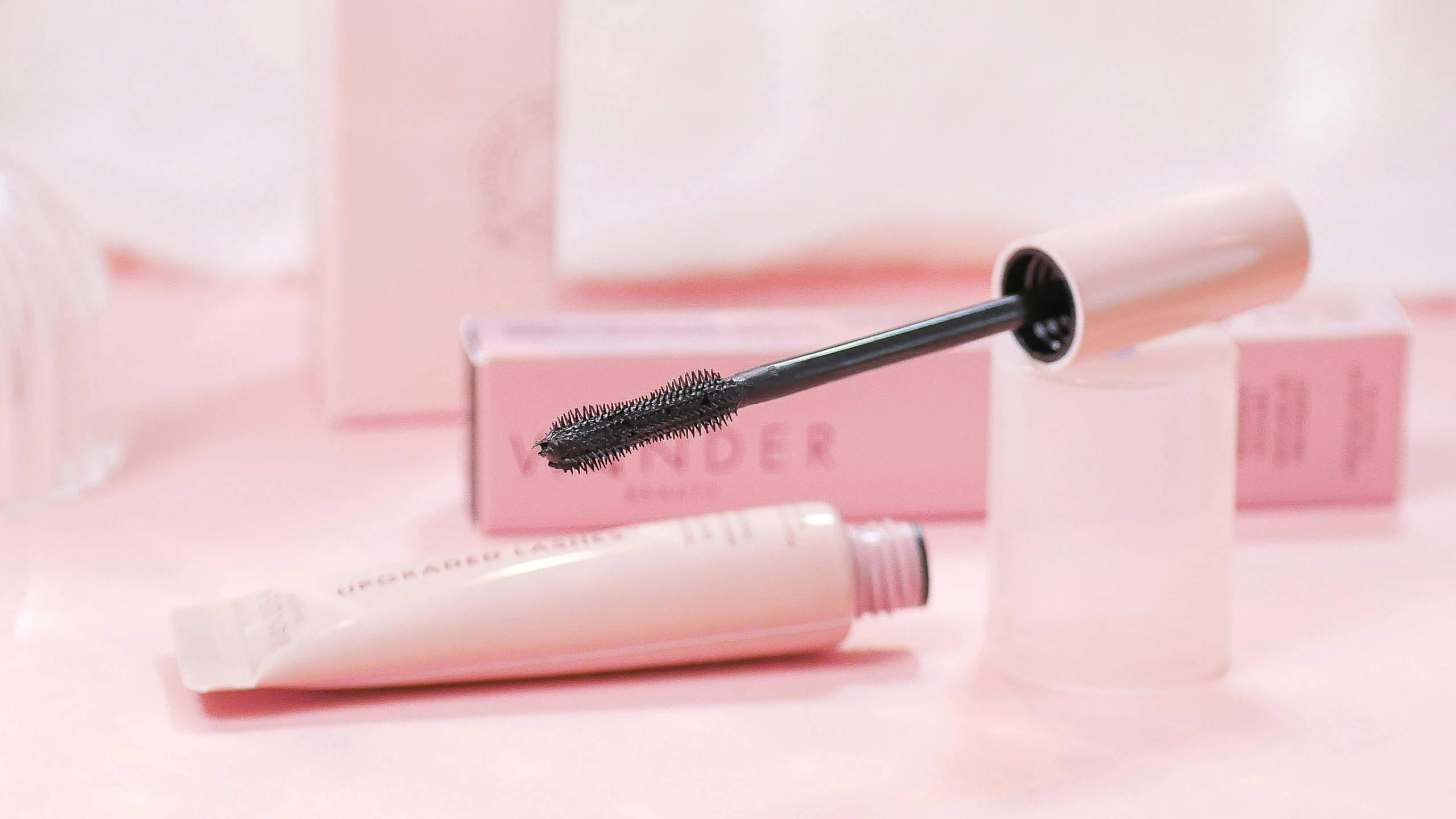 a black mascara with a tube inside of it sitting next to a package