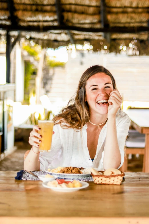 a girl sitting down at a table with a drink and food