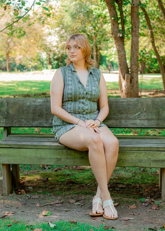 a woman sitting on top of a bench next to trees