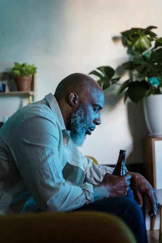 a man sits while he eats soing from a bottle