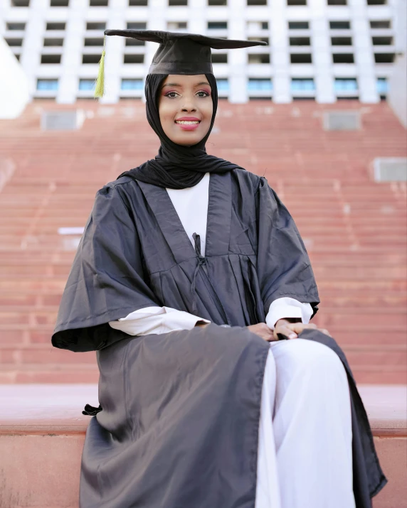 a smiling woman sitting in a graduate gown