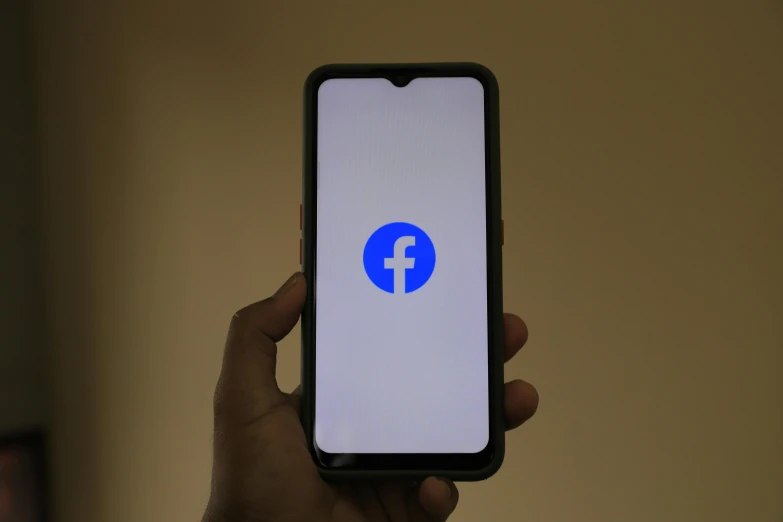 someone is holding a cell phone with the facebook logo on it