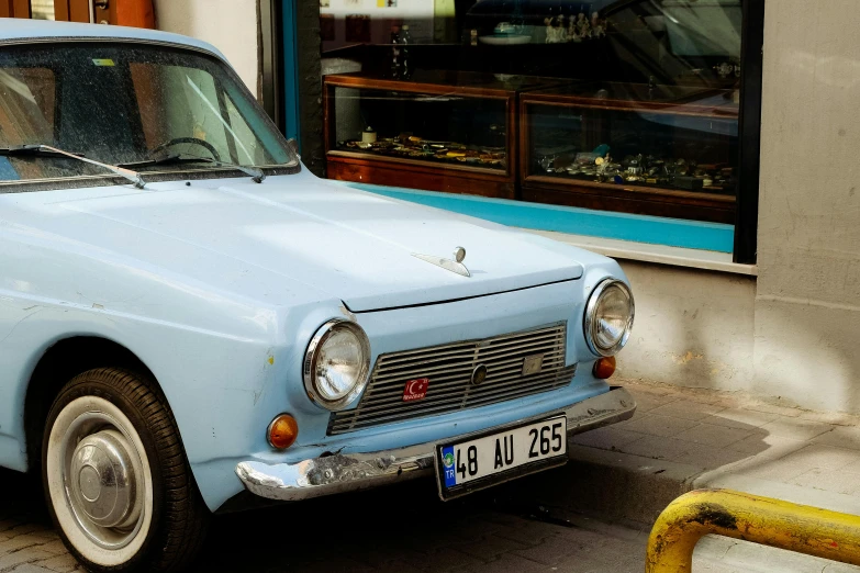 an old blue car parked on the side of the street