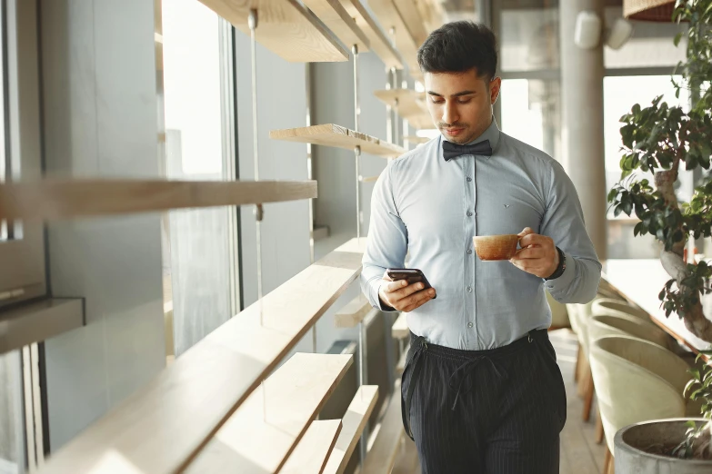 man in white shirt and bow tie checking his cell phone