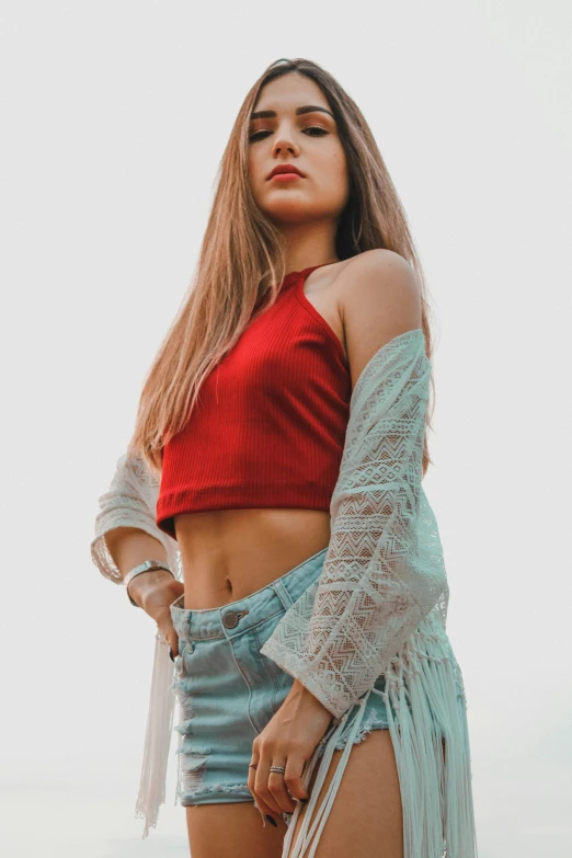 a woman wearing a top and denim shorts poses in the desert