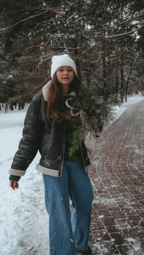 a woman holding onto a pine tree in the snow