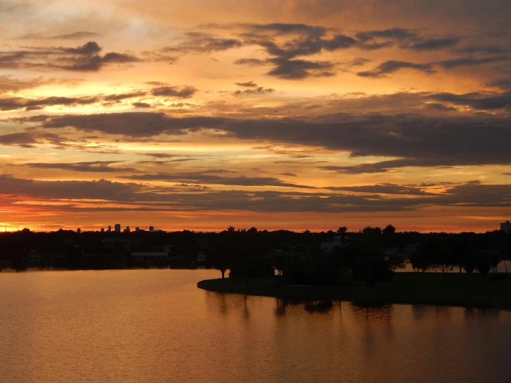 a lake at sunset with some clouds in the sky