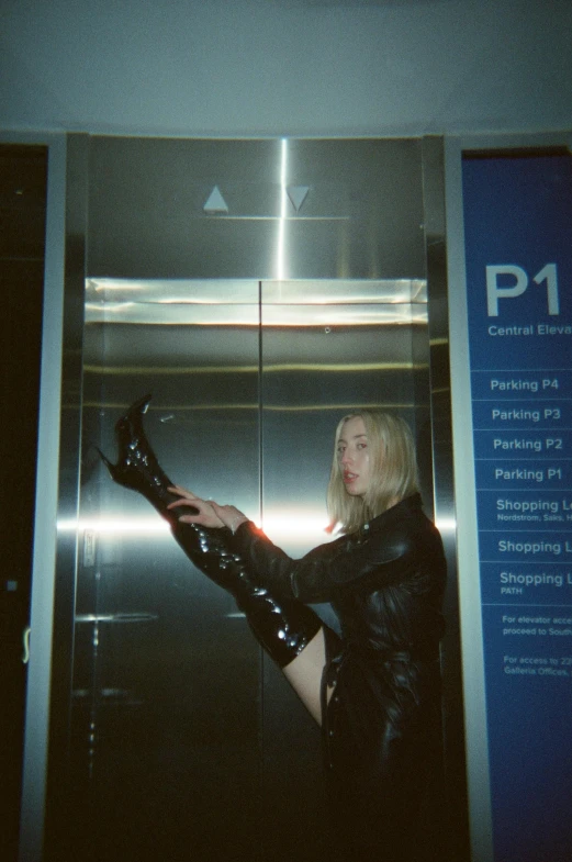 a woman in latex holding soing up in the elevator