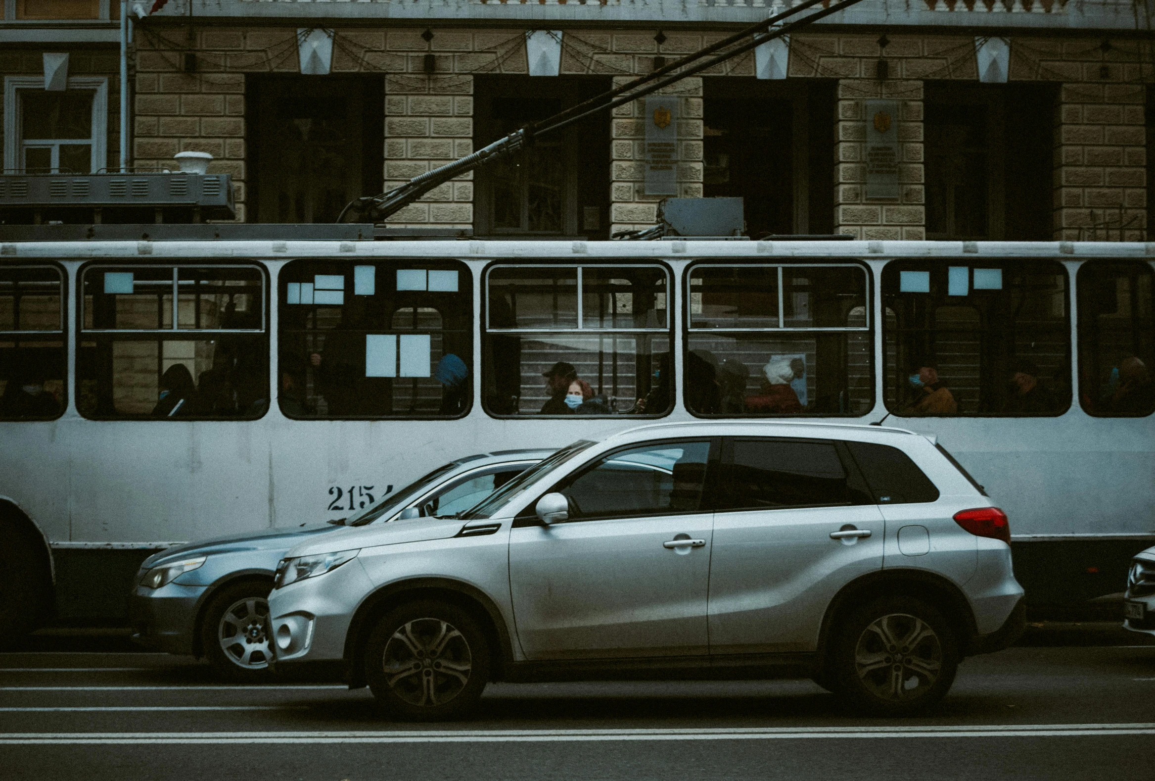 a white vehicle on a city street with a public transit bus