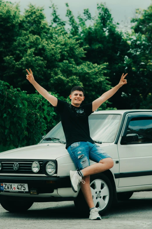 a man sitting on the side of a white car