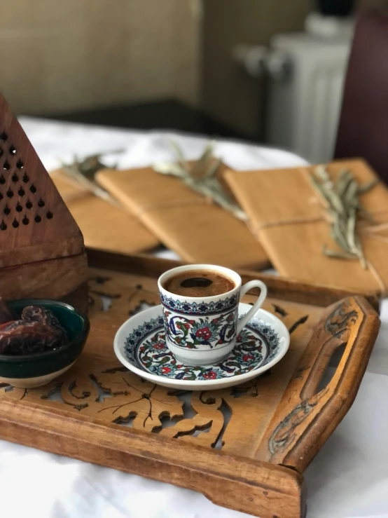 a table with a tray and plate with an open lid and a mug and saucer on it, sitting next to small brown bowls and napkins on top