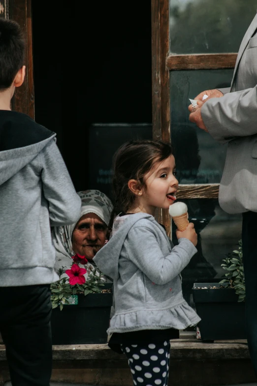 a little girl eating cake with people looking on