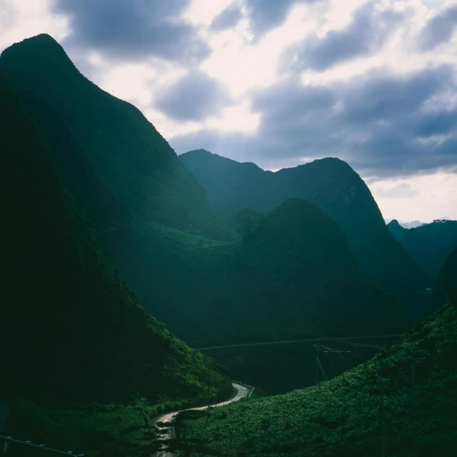 the sun setting on some mountains with a river in between