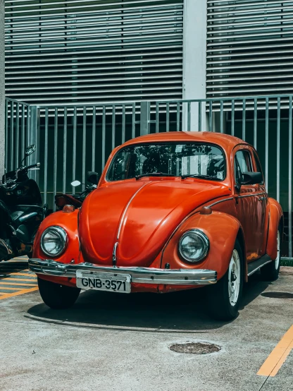 an orange vw bug parked in front of a tall building
