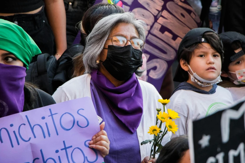 a woman holding a sign wearing a face mask