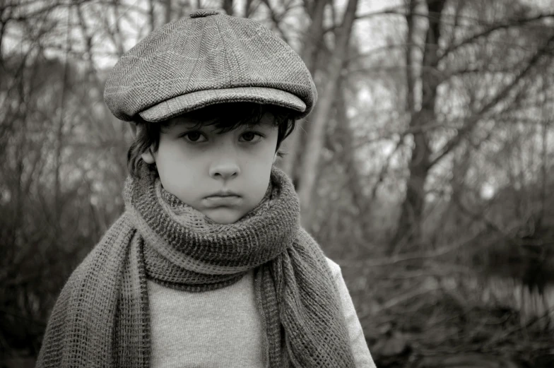 a child in hat, scarf and scarf in front of trees