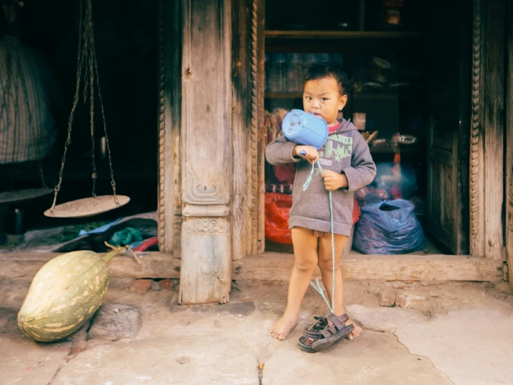 a boy standing outside his home in an asian village