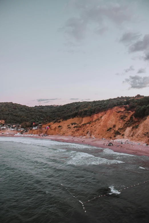 a beautiful beach at dusk with people on the sand and hills in the background