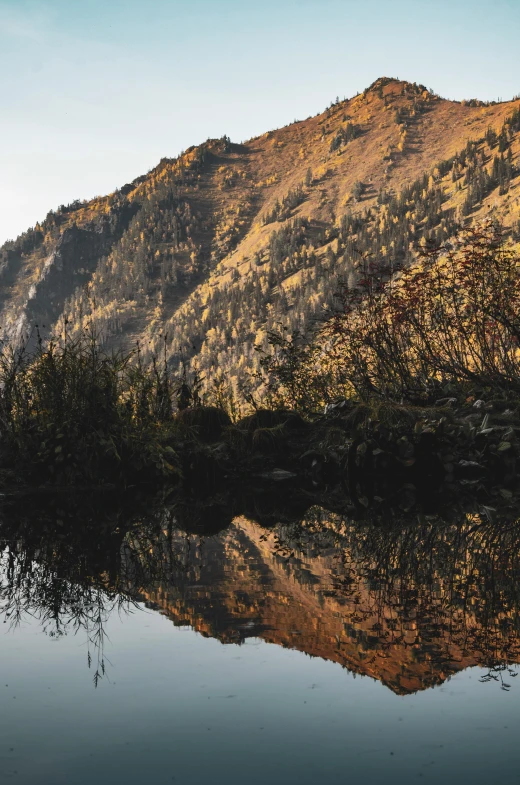 a mountain reflects on the still water of the lake