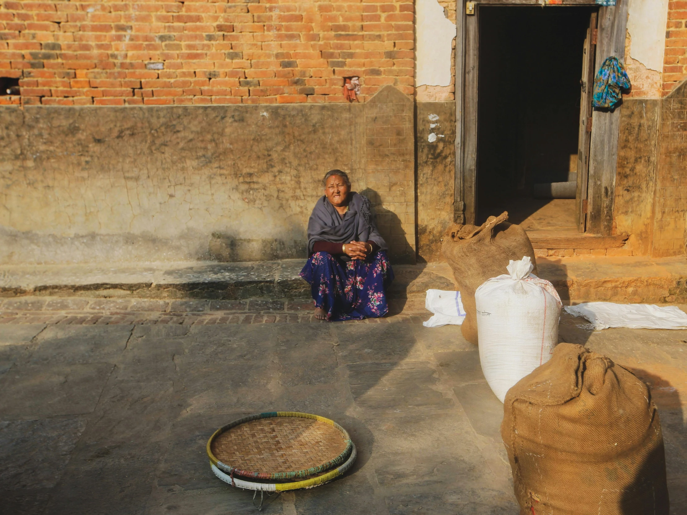 woman sits in front of a brick house