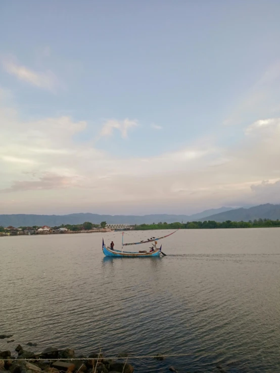 a long boat is on a river in front of mountains