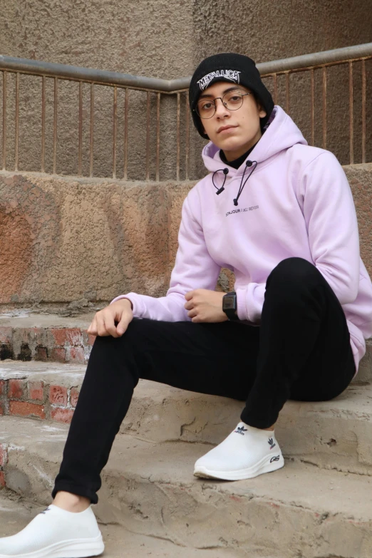 a guy wearing a hat, sweatshirt and black pants sits on the steps