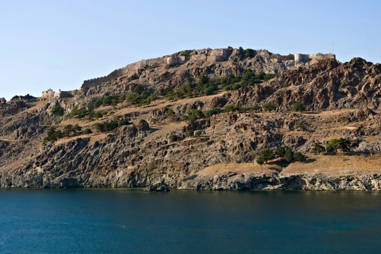 a large body of water next to a mountain with trees