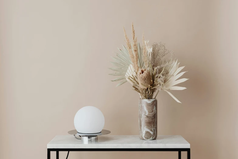 a vase on a table with a lamp beside it