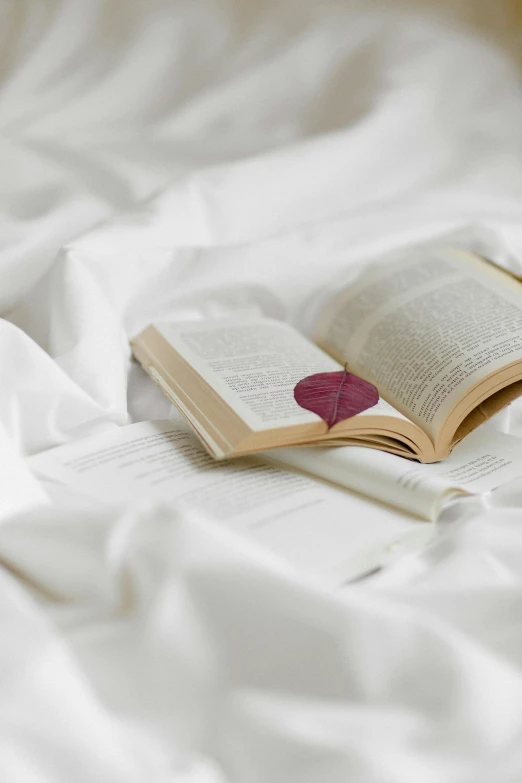 a book laying on top of a white bed