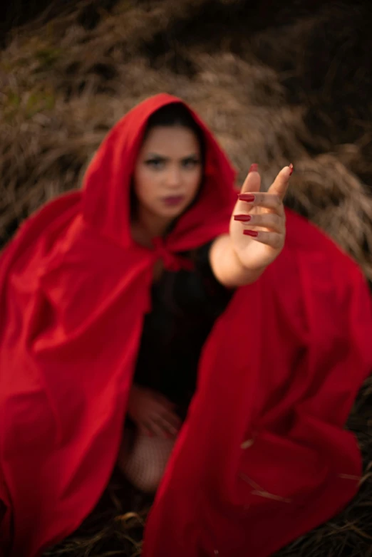 a woman in red sitting in the middle of some grass