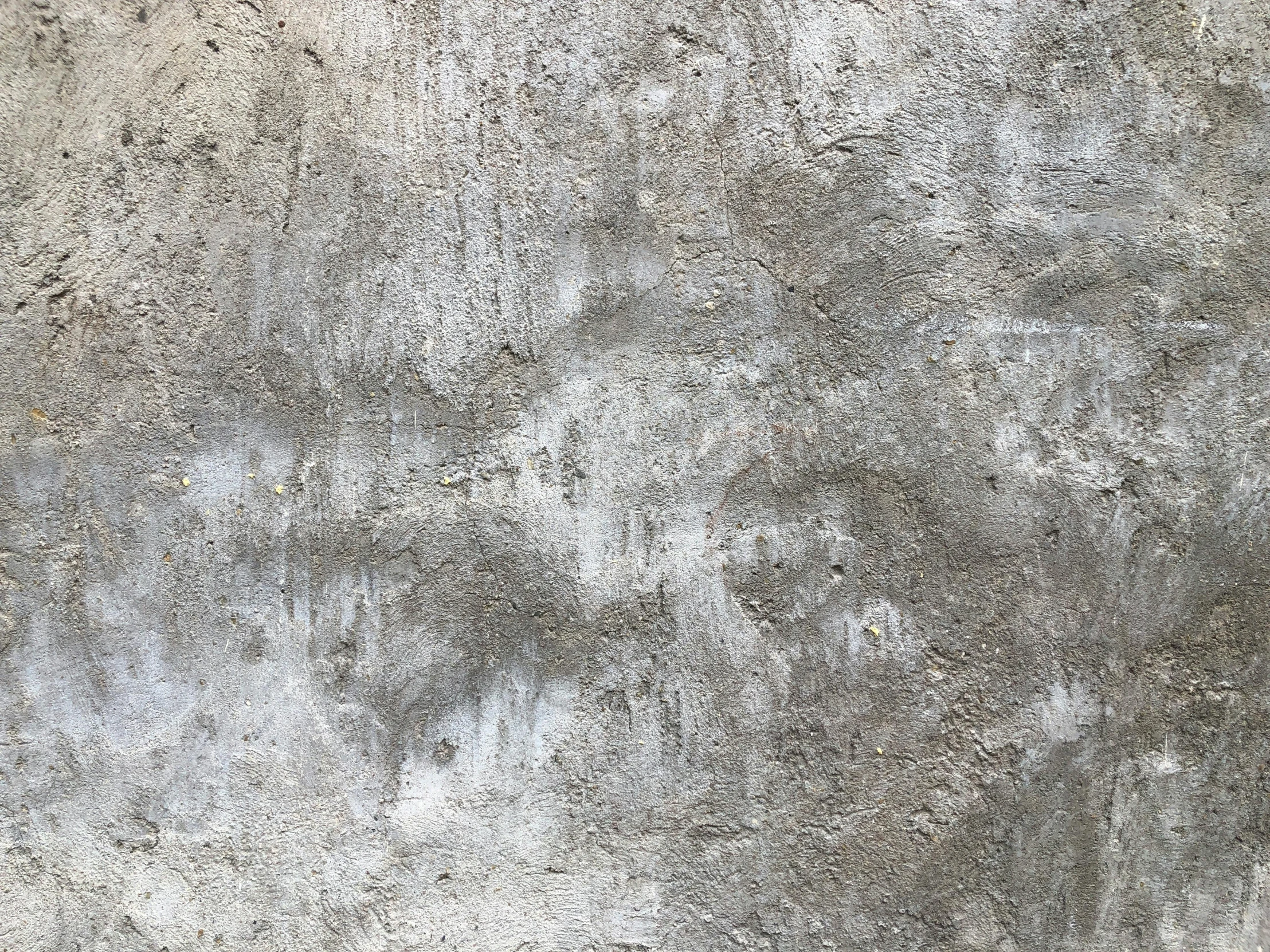 the surface of an old, grey concrete wall with no mortar