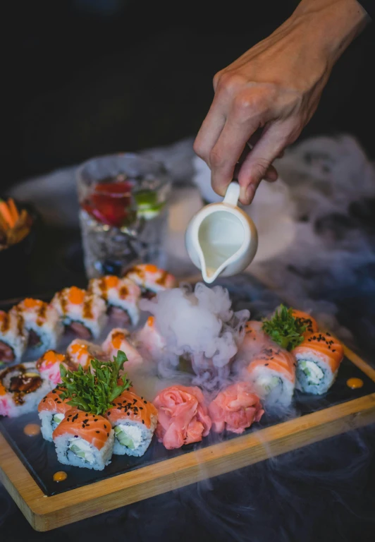 someone serving sushi from the tray with steam rising