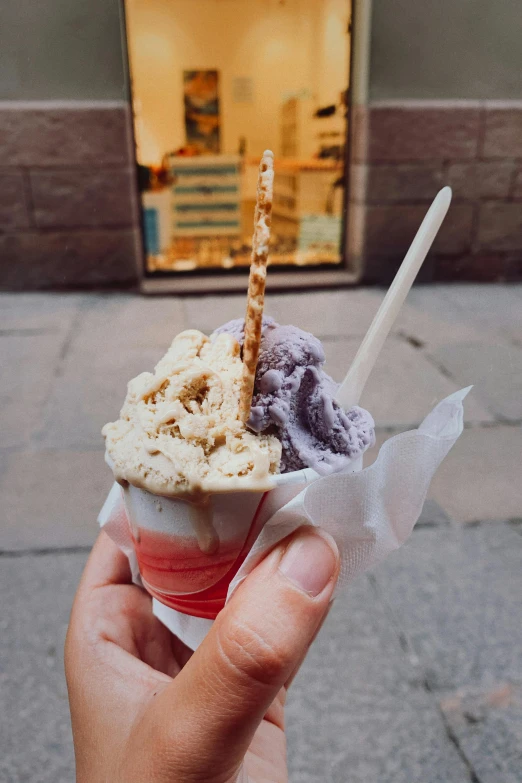 someone holding a cup with ice cream outside a building