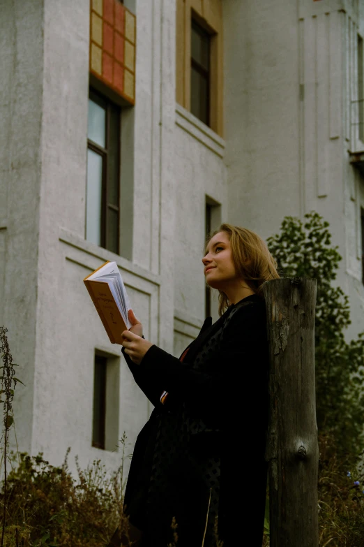 woman in long dress holding a piece of paper next to a fence