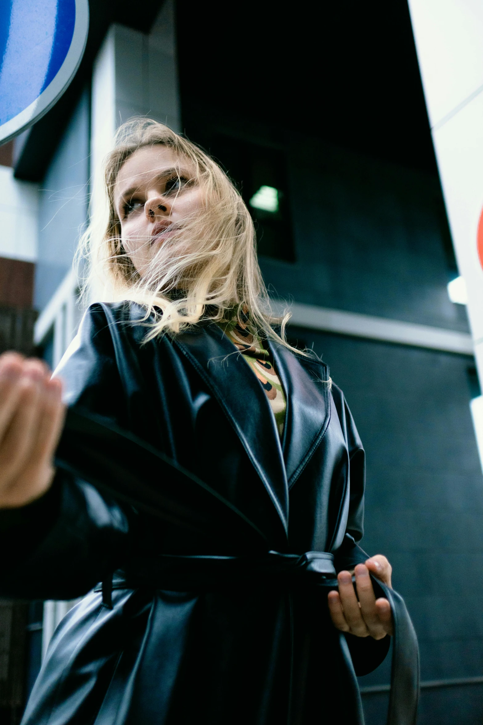 a woman in black jacket standing by sign