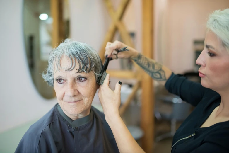 a lady getting her hair cut while another person watches