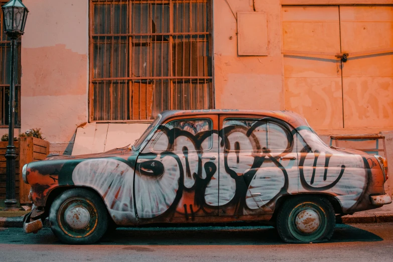 old car painted with grafitti on side of building