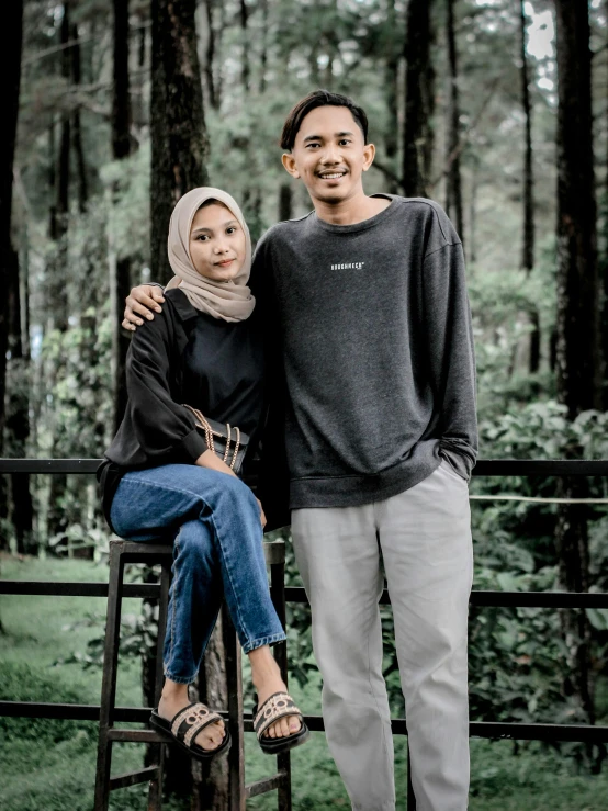 two people are standing on the fence in front of trees