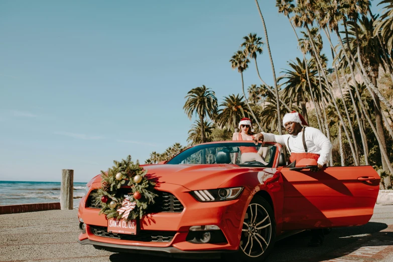 two people standing by a red car with tropical decorations