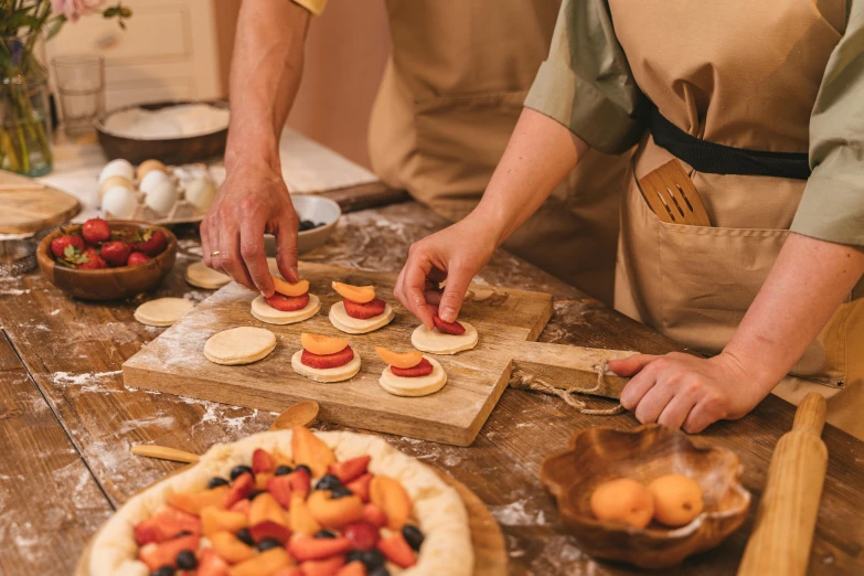 a cook puts strawberries on a fruit tarts