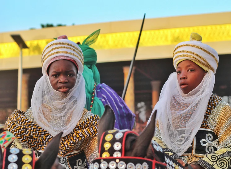 two african women in costume with long poles