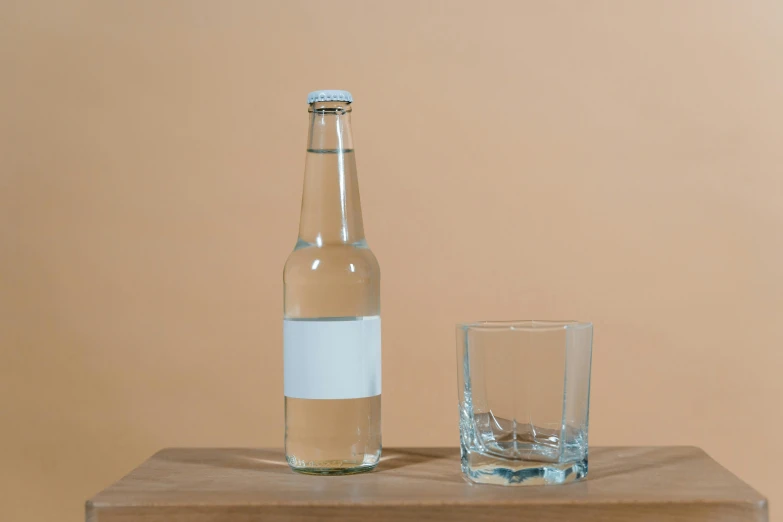 a bottle with a glass sitting next to it on a table