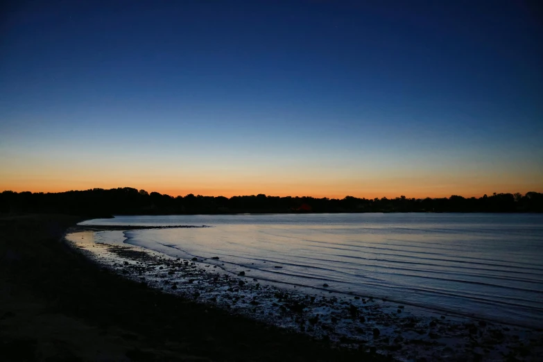 the sun rises over a lake with some dark water