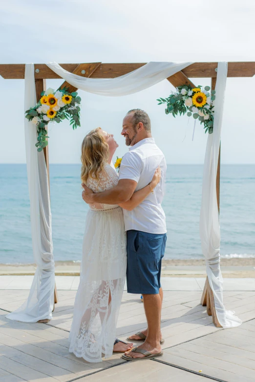 a bride and groom emce under an archway by the ocean