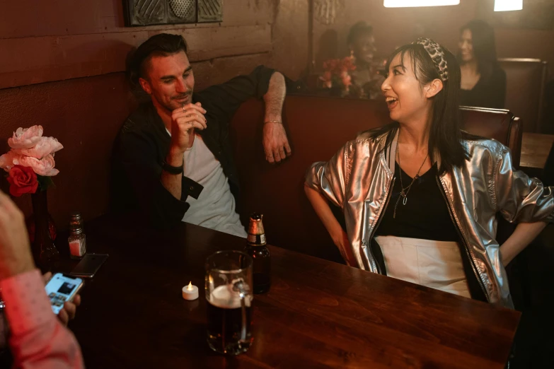 two people in a restaurant sitting at a wooden table with drinks