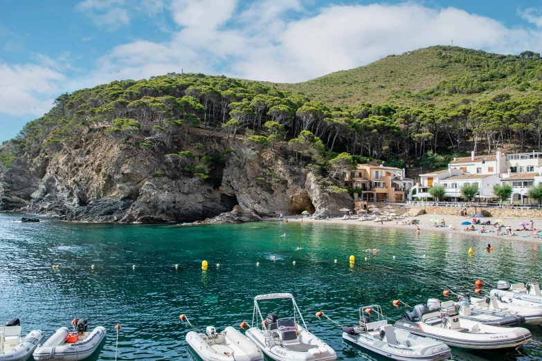 small boats docked at the dock with people swimming on the shore