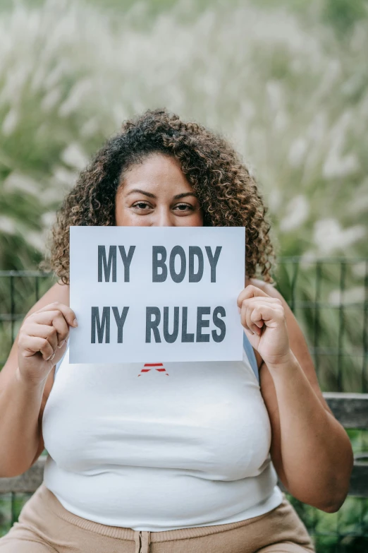 a woman holding up a sign saying my body my rules