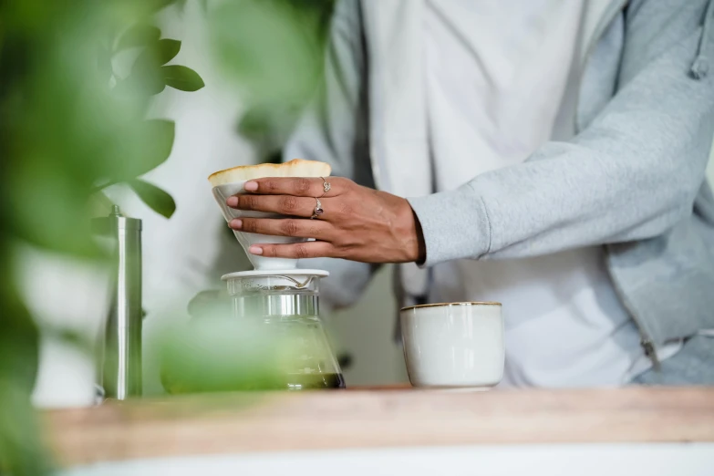 a person putting coffee into a white cup