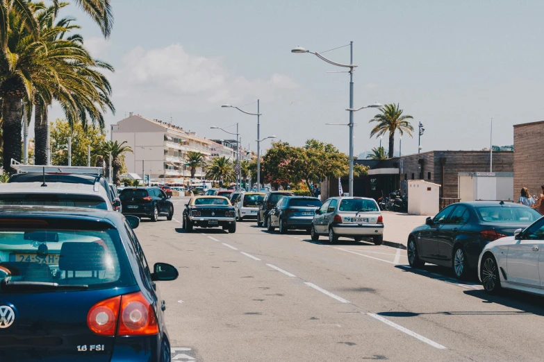 a street full of cars driving down it near palm trees