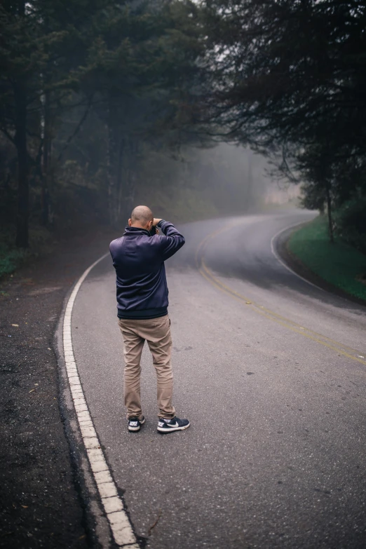 a man is taking pictures while standing on the road